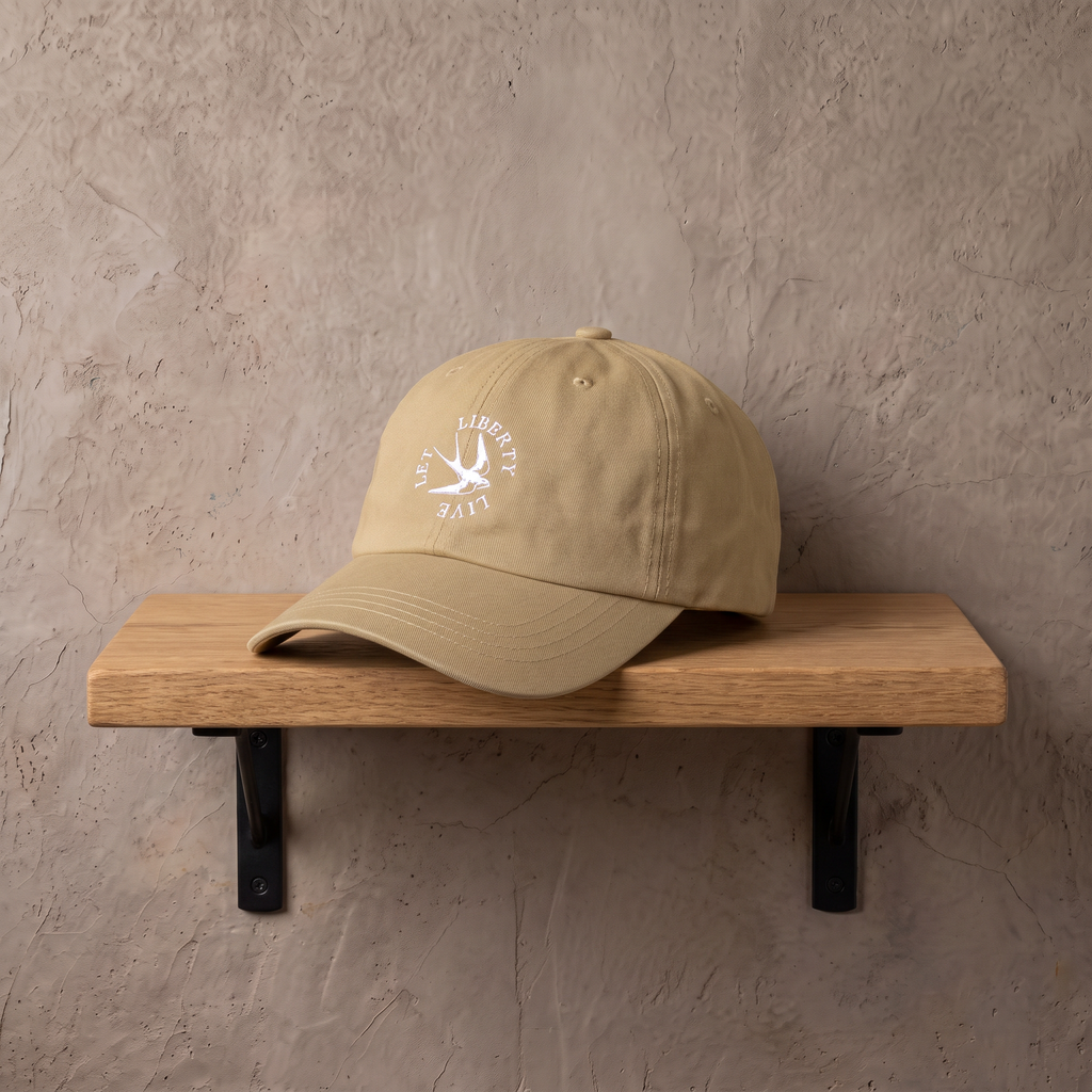 Let Liberty Live cap op een eiken wandplank tegen een stucwerk muur