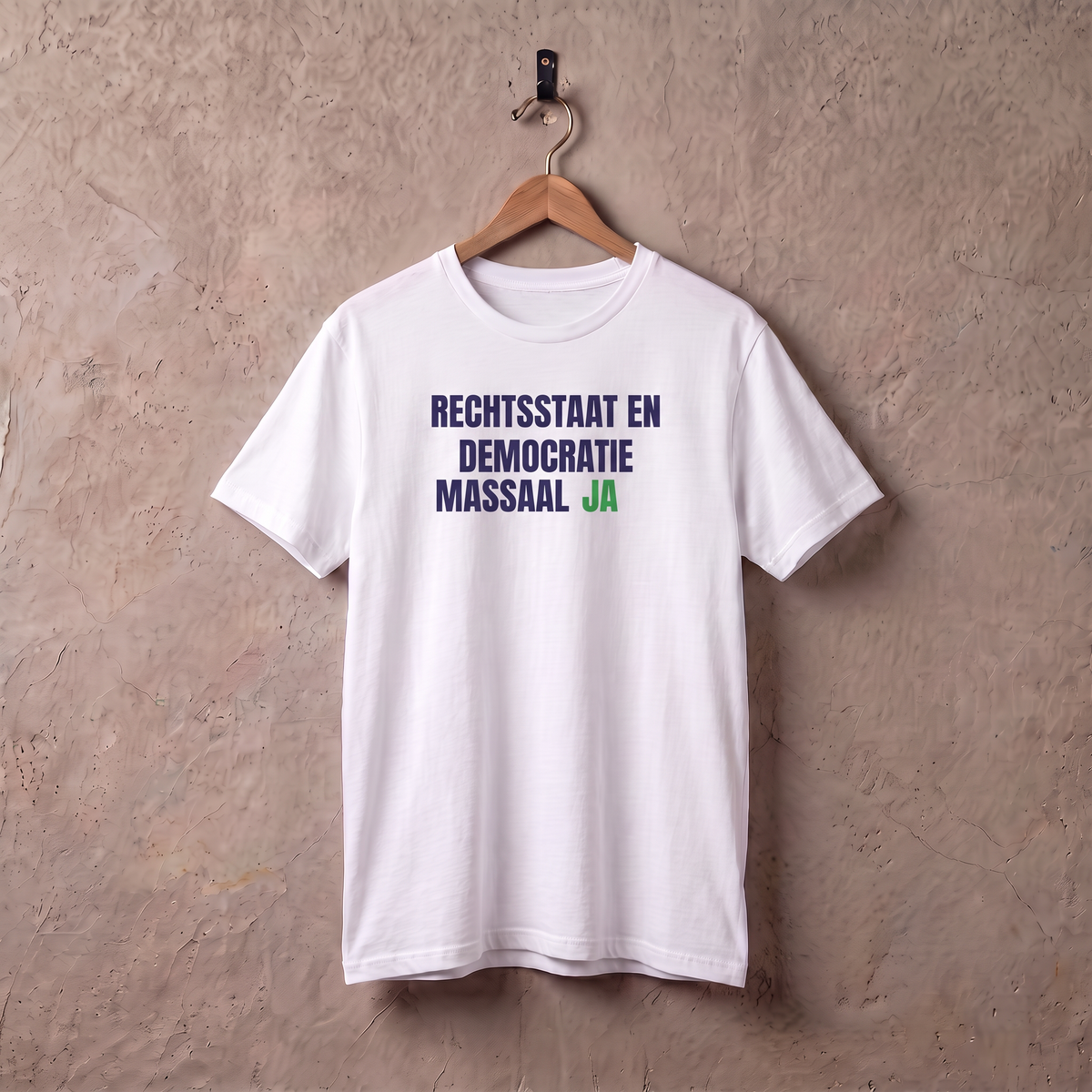 Wit t-shirt Rechtsstaat en Democratie, massaal ja! aan een houten hanger tegen een stucwerk muur